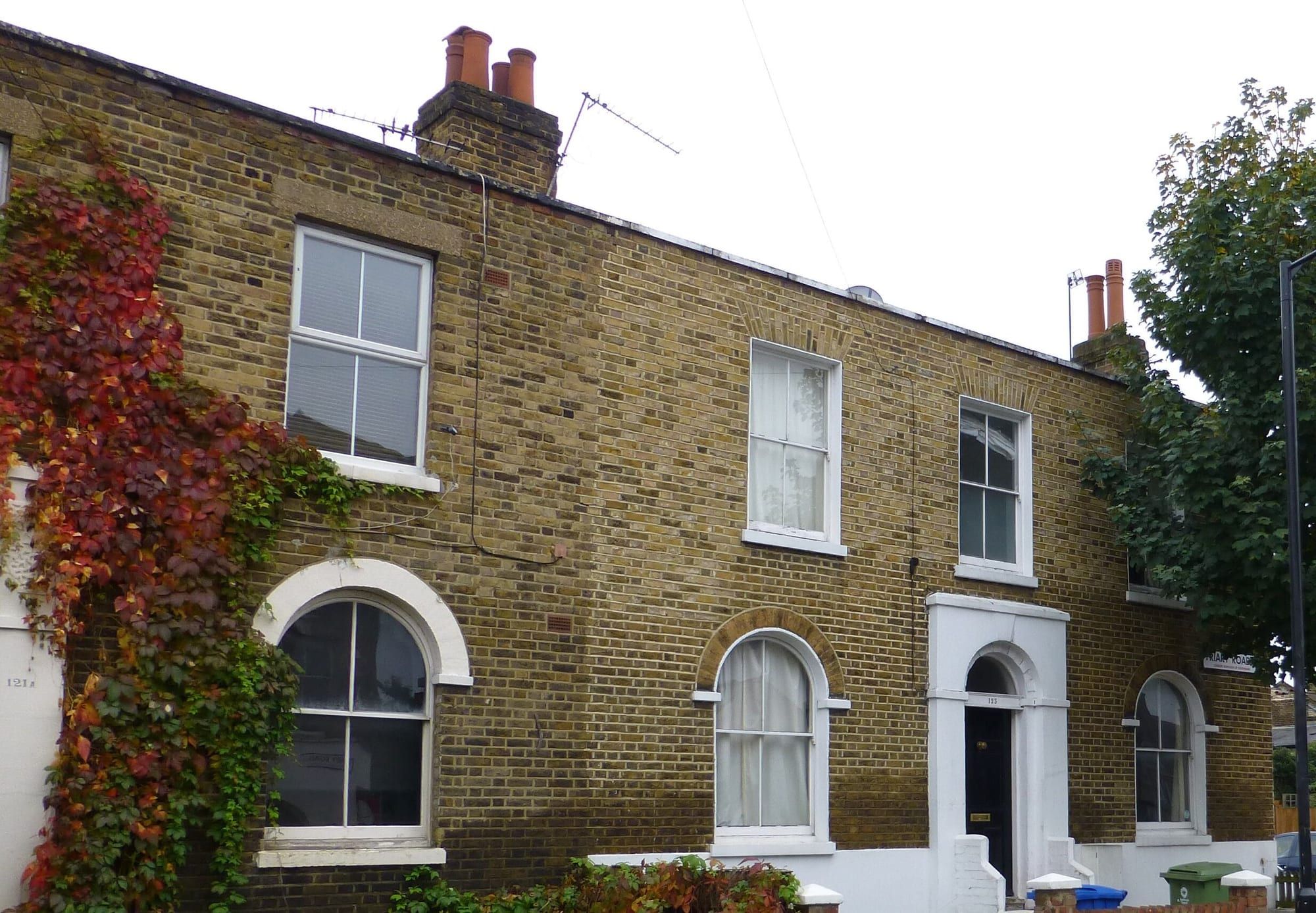 A two-storey Victorian brick house with arched windows and autumn creeper