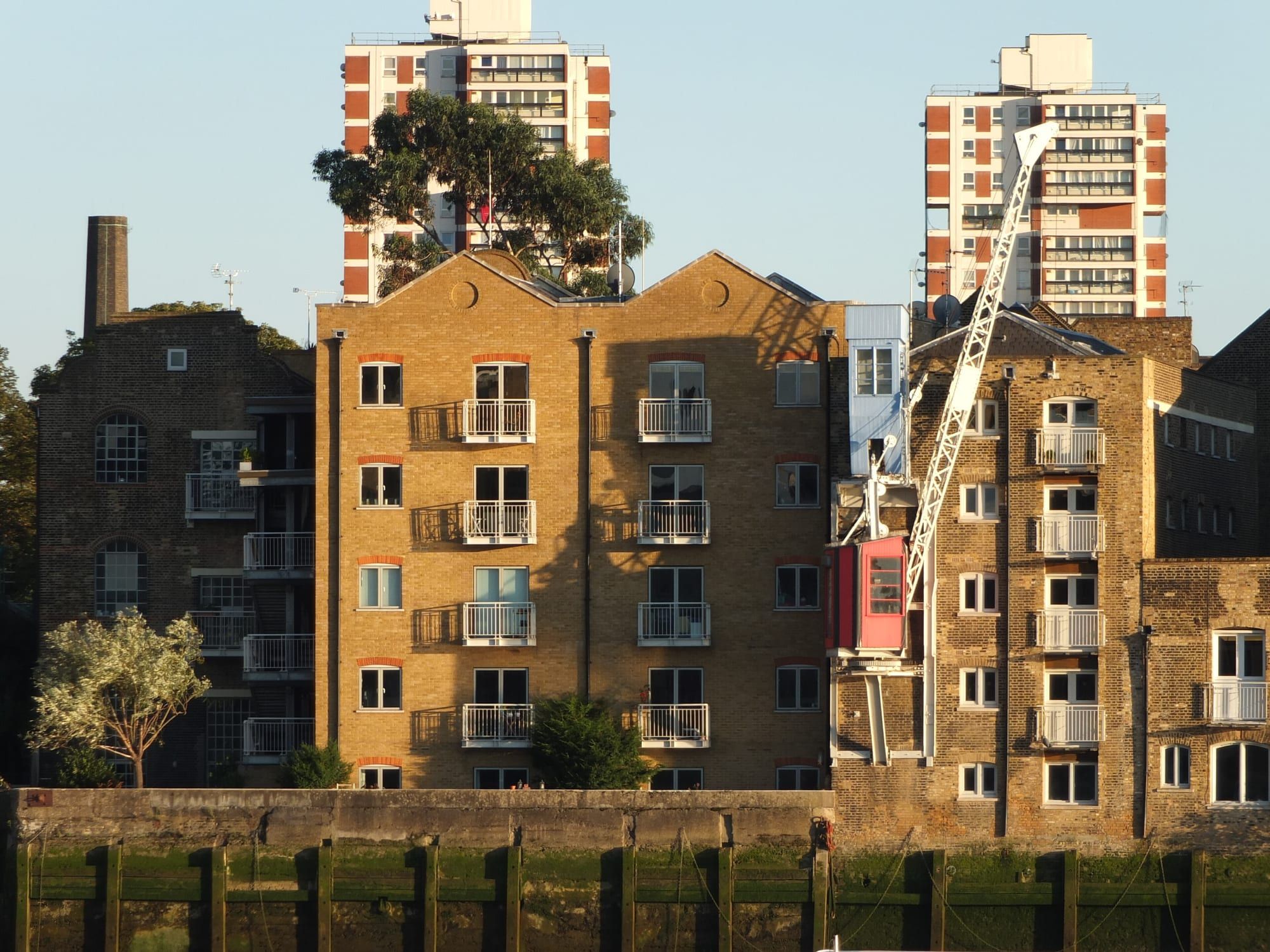 Converted riverside warehouses with small balconies in low evening sun