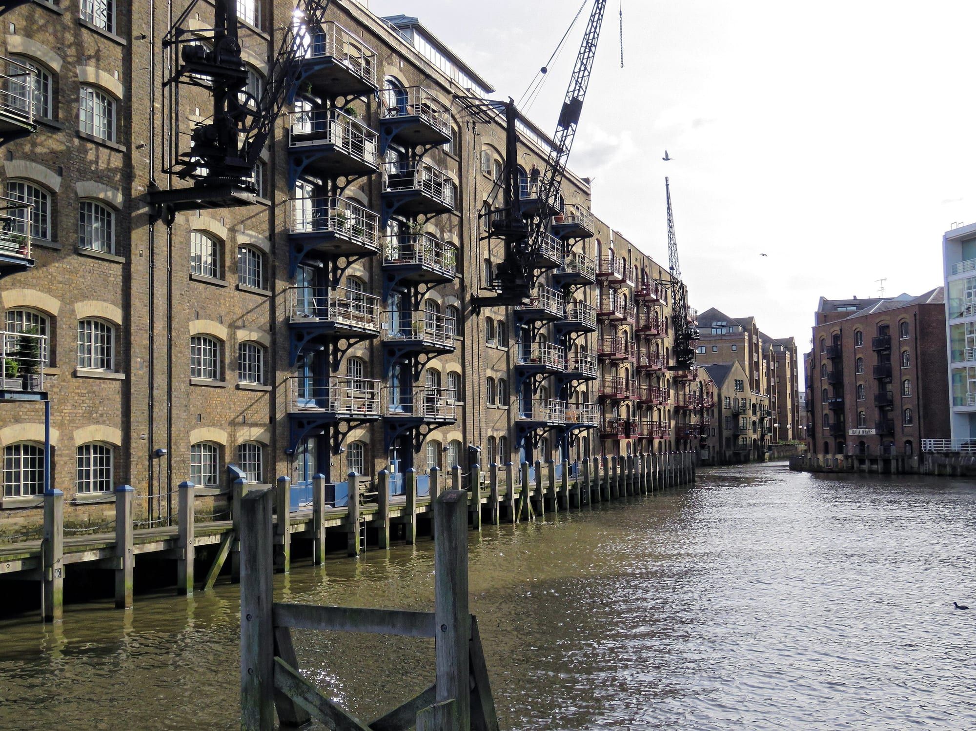 Warehouse apartments with iron balconies and old cranes beside a tidal dock